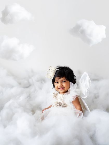 A happy little angel sitting on a cloud. The hanging clouds add a lovely touch of whimsy to the scene.
