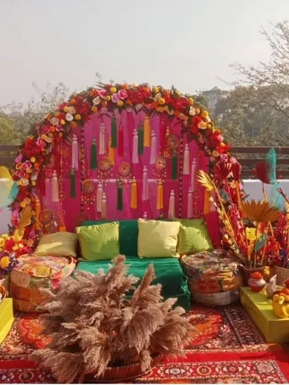 A perfect rooftop Mehandi setup with a vibrant, bohemian vibe. We used a floral arch, colourful tassels, low seating with gaddas, and lots of props for a festive and photogenic event.