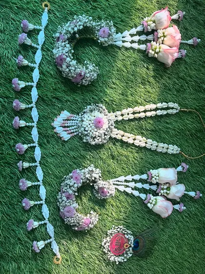 A partial floral jewellery set designed for a baby shower, featuring bajuband, a brooch, and a veni, all made with fresh flowers.