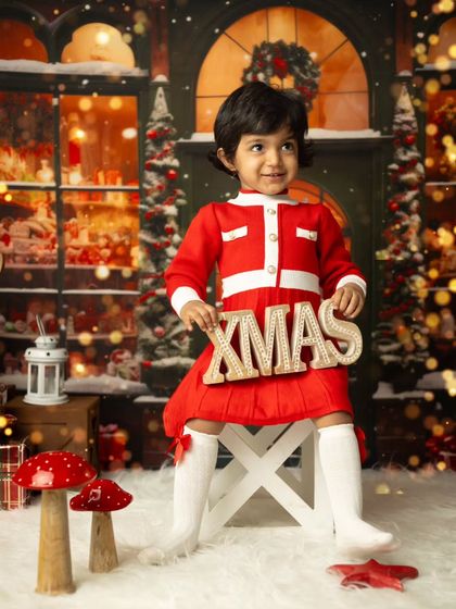 A picture-perfect Christmas card photo. This little girl holds an 'XMAS' sign in our beautifully decorated studio.