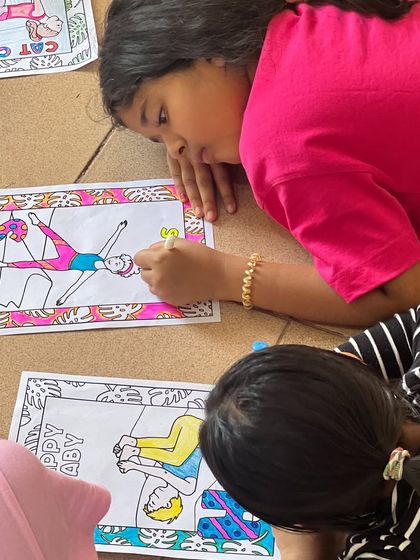 Young students enjoy a moment of creative expression, coloring pictures of asanas like Happy Baby pose. Art and yoga are wonderful tools for mindful development.