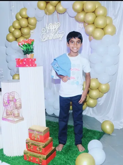 The birthday boy posing in front of his elegant gold and white balloon arch decoration.