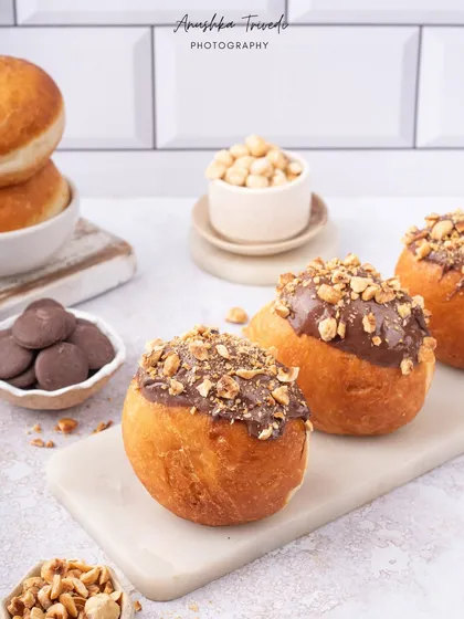 Hazelnut-filled bombolonis, looking rich and decadent. The clean, bright styling on a marble slab gives them a modern and chic bakery vibe.