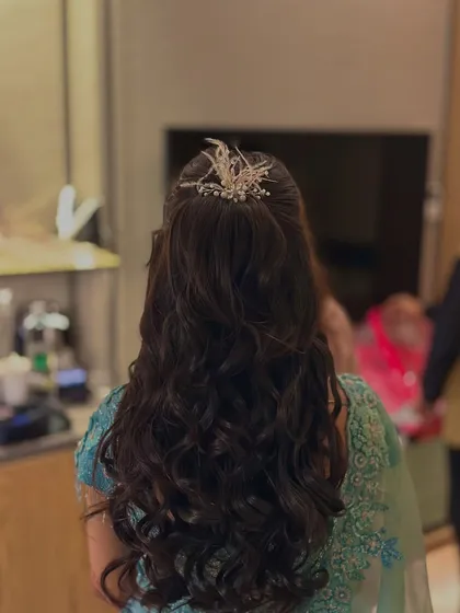 A half-up hairstyle with big, bouncy curls, ready for an engagement. The look is completed with a statement silver hair accessory.