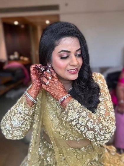 A candid moment of the bride adjusting her earring. This shot provides a great view of her soft curls and the subtle shimmer on her eyes.