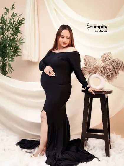 A full-length portrait showing the elegant silhouette of the black gown. This look is timeless and flattering for every mom-to-be.