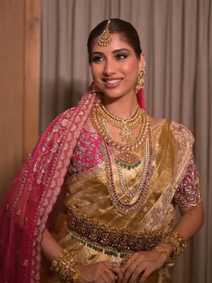 A smiling portrait of a South Indian bride. The makeup enhances her features with a soft glow, balancing the opulence of her Kanjeevaram saree and heavy gold jewelry.