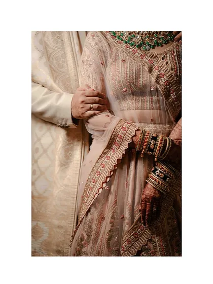 A close-up on the details: the bride's hand, adorned with bangles and henna, resting on the groom's arm. A simple, powerful symbol of their union.