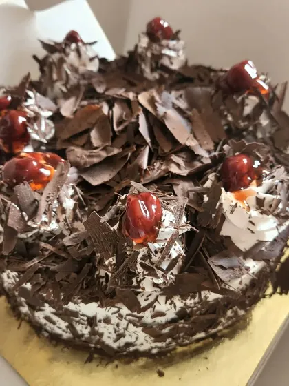 A classic Black Forest cake, generously topped with chocolate shavings and cherries. A timeless favorite for any occasion.