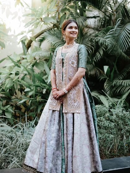 A full-length portrait of the bride at her Mehendi. The minimal makeup look perfectly balances her detailed outfit, creating an overall aesthetic that is elegant, chic, and effortlessly beautiful.