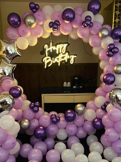 A purple, pink, and silver balloon ring with a neon sign. This setup is great for smaller indoor spaces, adding a lot of visual impact without taking up too much room.