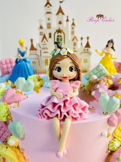 A close-up of the beautiful, handcrafted doll topper on the Candyland princess cake. She sits in front of a castle, surrounded by a world of sweets.