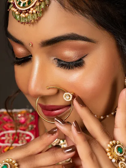 A close-up beauty shot from a bridal shoot, focusing on the eye makeup, nath, and henna-colored nails. This is perfect for a makeup artist's portfolio or a beauty brand.