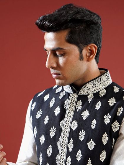 A classic black Jawahar jacket is elevated with contrasting white floral embroidery. This timeless piece is versatile enough for any festive occasion, offering a look of effortless elegance.