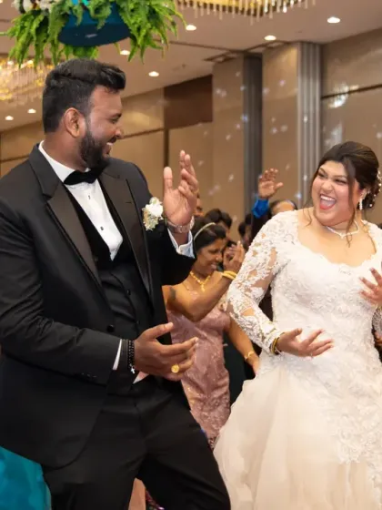 Pure happiness on the dance floor. This candid photo captures the bride and groom laughing and dancing together, surrounded by their loved ones.