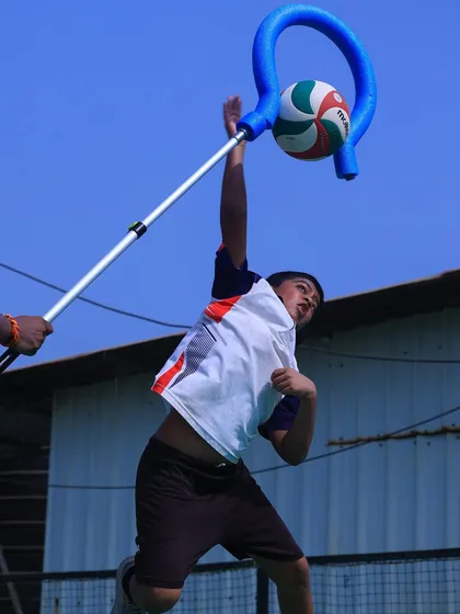 A young player uses a handheld spike trainer to perfect his arm swing and contact point. This innovative tool helps build correct muscle memory.