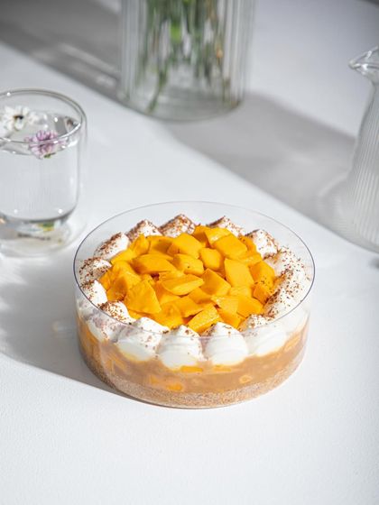 A close-up of our Mango Tres Leches, topped with fresh mango and a dusting of cocoa.