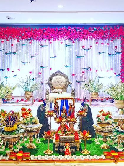 A baby shower setup with a backdrop of hanging red flowers and bird motifs, creating a vibrant and lively atmosphere.