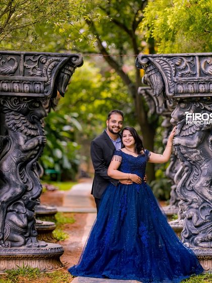 A romantic pose framed by ornate stone pillars in the garden.