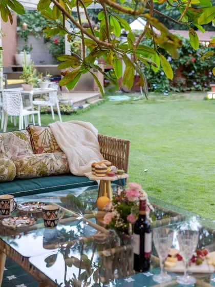 A festive outdoor table setting, ready for a garden party. The view looks across a manicured lawn, suggesting a perfect space for celebrations and cozy gatherings under the open sky.