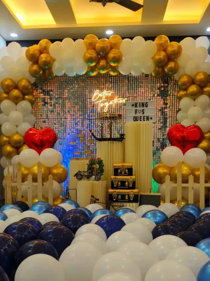 This is the gold, white, and blue anniversary decoration under bright, warm lighting. The heart-shaped balloons are a popular add-on for romantic events like anniversaries or proposals.