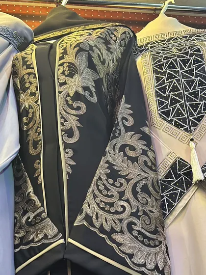 A closer look at the stunning gold floral embroidery on a black abaya. This is a truly luxurious piece, sourced directly from a trusted 'kedai' in Dubai.