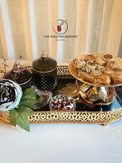 A perfect harmony of taste and elegance. This luxury gift set combines indulgent baklava, premium dry fruits in decorative jars, and a beautifully scented candle, all presented on an ornate golden tray.