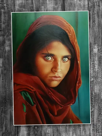This stunning oil painting is a recreation of the iconic 'Afghan Girl'. The artist has masterfully captured the subject's intense eyes and the rich textures of the fabric, showcasing deep proficiency in the oil on canvas medium.