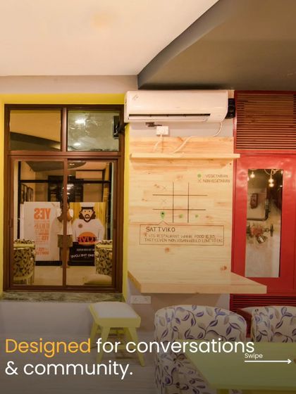 This nook in the cafe is designed for conversations and community. The interactive tic-tac-toe board on the wall and the comfortable, patterned seating create a playful and engaging corner for guests to enjoy.