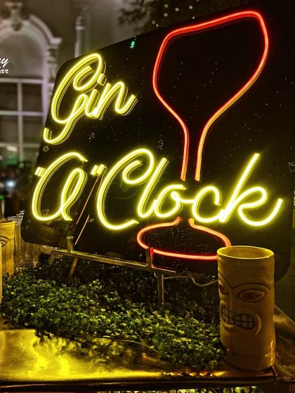 A close-up of the 'Gin O' Clock' neon sign, which adds a fun and thematic touch to any event. The warm yellow glow creates an inviting atmosphere for guests to gather and enjoy a drink.
