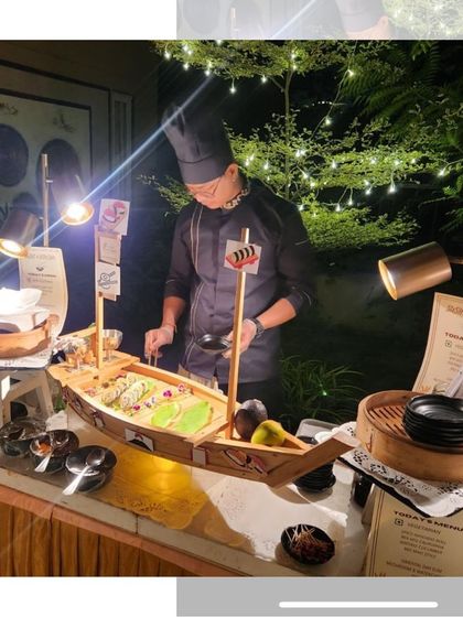 Our sushi chef meticulously preparing rolls at a live station during an evening event. The setup is complete with professional lighting and all the freshest ingredients.