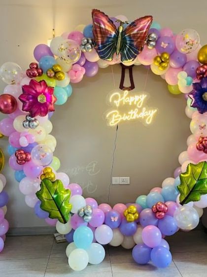 A vibrant butterfly-themed balloon ring for a 5th birthday. This full circle of colorful balloons is decorated with various foil butterflies and flowers, creating a stunning photo backdrop.
