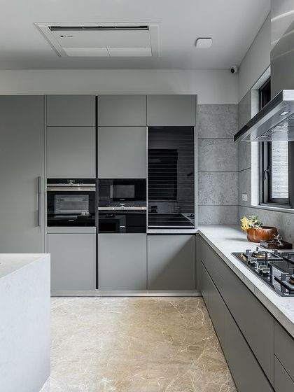 The kitchen's main wall includes integrated Siemens appliances and a sleek hob, all set against a backdrop of large-format tiles that mimic the look of concrete.