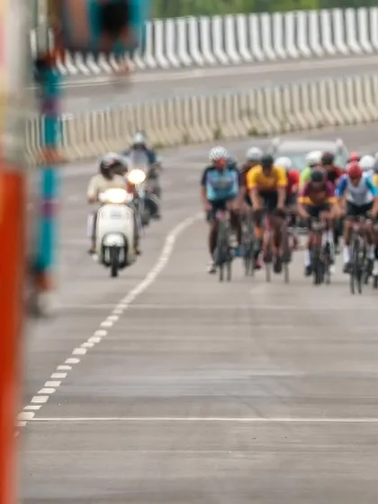An elite rider leads the peloton past a large truck, a reminder of the dynamic and sometimes challenging environment of road racing.
