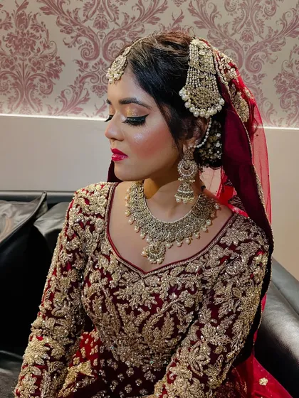 A close-up of another Nikaah bride. The makeup features dramatic, golden-toned eyes and a bold red lip, creating a look of regal beauty.
