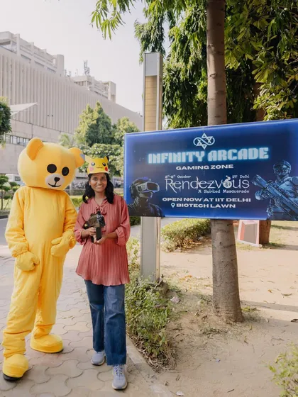 Posing with our mascot in front of the Infinity Arcade gaming zone banner at IIT Delhi. It’s a great way to show the fun, festival atmosphere I create.