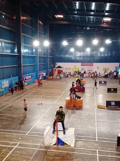 Our facility is fully equipped to host large-scale badminton tournaments. This wide shot shows our courts set up for a competition, complete with umpire chairs, spectator seating, and official branding, demonstrating our capacity for professional events.