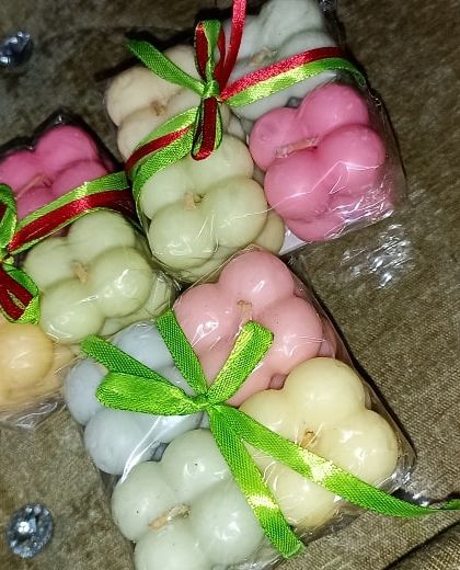 These small bubble candles are wrapped with festive ribbons, showing a simple yet effective way to package your handmade items for Christmas or as party favors.