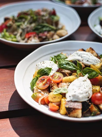 A table with multiple bowls of our seasonal Mango Tuscan Salad, ready for a group to enjoy.