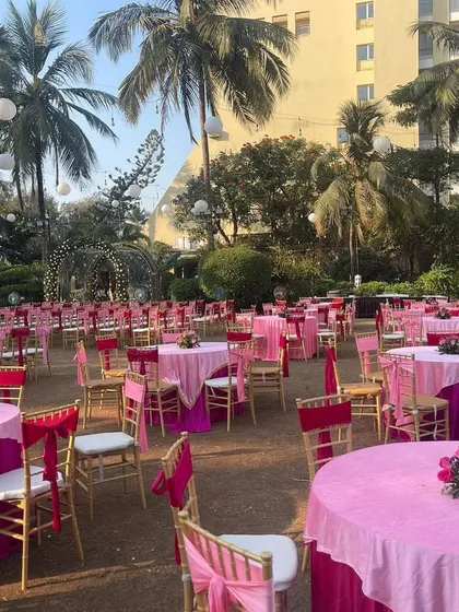 An overview of a pink-themed daytime wedding seating arrangement. The round tables with pink linens and matching chair sashes create a beautiful and organized look for guest dining.