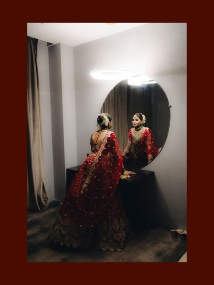 The bride looking at her reflection in the mirror before her reception. This is a classic, cinematic shot full of anticipation.