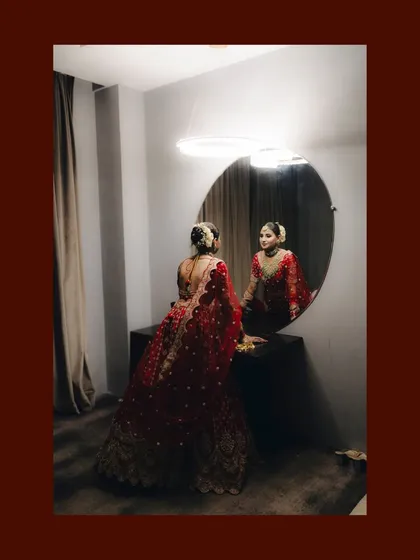 The bride looking at her reflection in the mirror before her reception. This is a classic, cinematic shot full of anticipation.