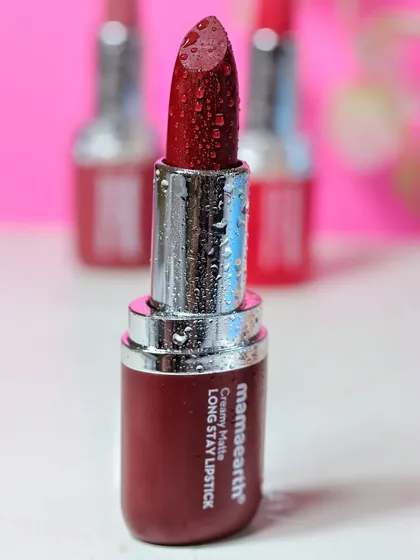 A focused shot on a single deep red Mamaearth lipstick, with other shades blurred in the background to create depth and highlight the hero product.