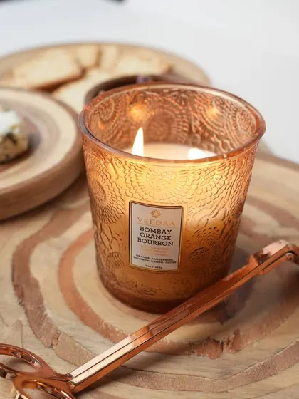 Our Bombay Orange Bourbon candle, captured here with a candle trimmer. This fragrance blends fresh orange and tangerine with the warmth of bourbon, creating a cozy and inviting atmosphere.
