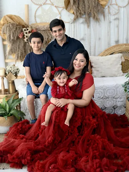 A gorgeous family of four, perfectly coordinated in red and navy. The mother's stunning red gown and the love shared between them make this a truly special portrait.