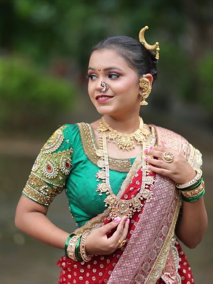 A side profile showcasing the intricate embroidery on the blouse sleeve and the layered necklaces.