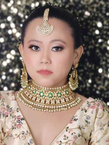 A simple and elegant look featuring a Polki choker with green stones and a matching maang tikka. This is a great choice for someone who prefers minimalist bridal jewellery.