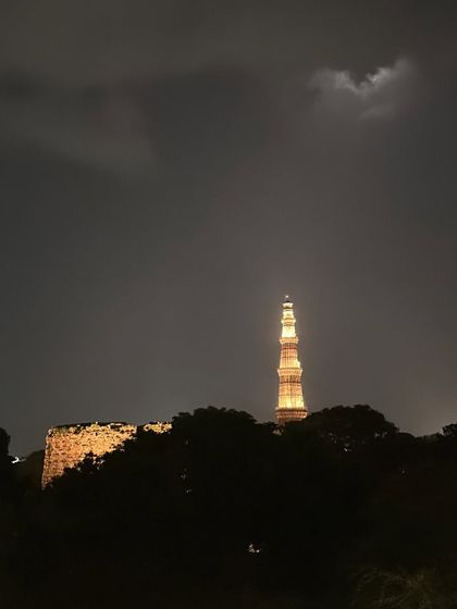 The view from our terrace is captivating day and night. Here, the silhouette of the Qutub Minar stands against a dramatic sky, a timeless icon of Delhi.