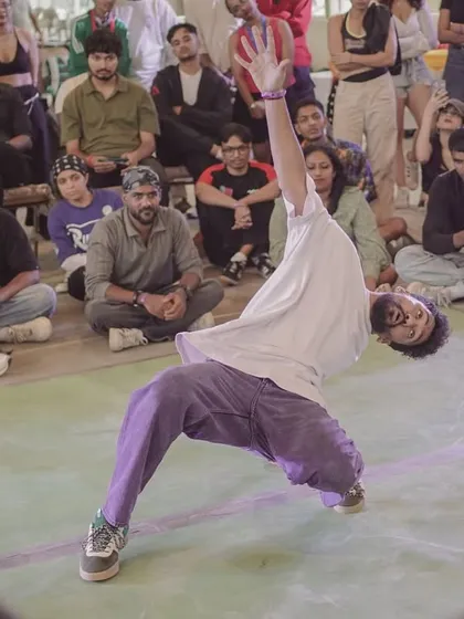 A dancer mid-power move during the 2v2 Open Style battle, showcasing incredible flexibility and control.
