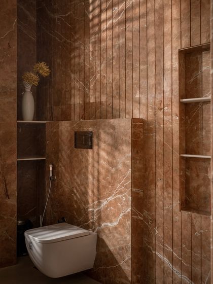 A detail of the terracotta bathroom, showing the built-in shelving and the beautiful texture of the stone walls, activated by the play of light.